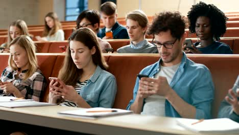 Multi-ethnischen-Gruppe-von-Studenten,-die-mit-Smartphones-während-des-Vortrags.-Junge-Menschen-mit-Social-Media-beim-Studium-an-der-Universität.