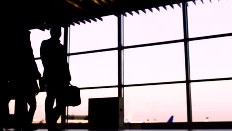 Silhouettes-of-business-people-walking-in-airport,-plane-takeoff-on-background