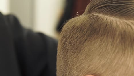 Mano-femenina-haciendo-el-pelo-hombre-corte-con-maquinilla-y-peine-en-peluqueria-de-cerca.-Peluquería-haciendo-peinado-con-máquina-de-afeitar-eléctrica