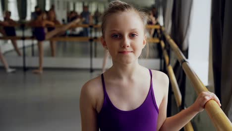 Porträt-von-schönen-Mädchen-Ballett-Tänzer,-Blick-in-die-Kamera-und-lächelnd-in-Ballett-Klasse-in-geräumigen-hellen-Dancehall-stehen-ab.-Kunst-und-Kindheit-Konzept.