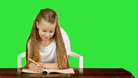 Little-girl-writes-to-writing-book-on-a-Green-Screen,-Chroma-Key