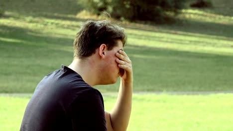 Hombre-joven-triste-deprimido-solo-en-el-inicio-del-parque-llorando