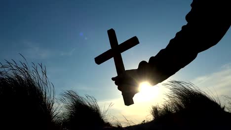 Silhouette-des-Menschen-"Hand-Kreuz-über-den-Sonnenaufgang---Konzept-zur-Religion-erhoben