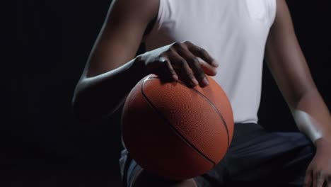 Unrecognizable-Basketball-Player-Sitting-on-Black-Background