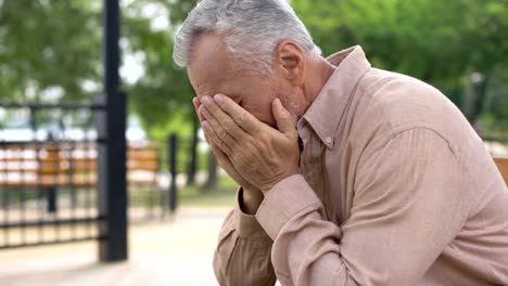 Triste-anciano-sentado-en-el-Banco-del-hospital-jardín,-pensionista-llorando-de-tristeza