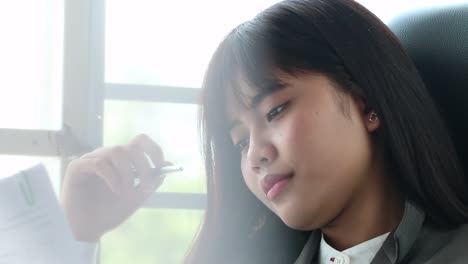 Portrait-of-Asian-female-student-thinking-over-working-homework-and-schedule-for-her-exam-test-school-in-future,-sitting-alone-by-window-in-home,-slow-motion-and-candid-shot