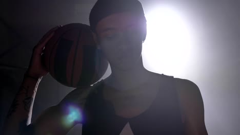 Basketball-player-with-tattoos-holding-ball-on-his-shoulder-and-looking-at-camera