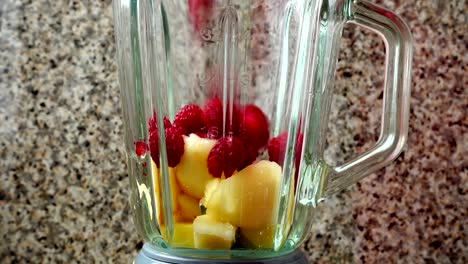 Füllung-in-den-Mixer-von-Stücken-von-einer-Birne,-Himbeeren-und-Bananen.	Vorbereitung-der-Smoothie-in-den-Mixer-geben.