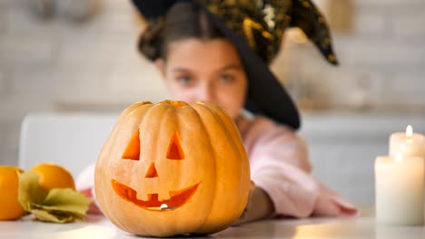 Brujita-mostrando-miedo-calabaza-de-Jack-o-Lantern,-preparando-para-la-fiesta-de-Halloween