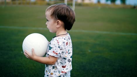 Kleiner-Junge-hält-den-Ball-in-seine-Hände-auf-dem-Fußballplatz