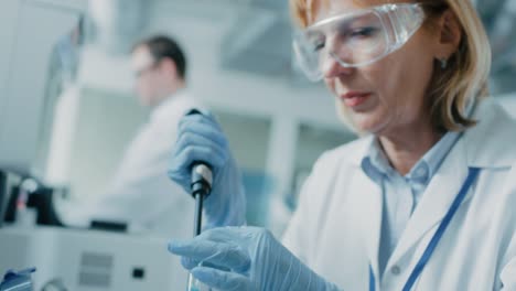 Close-up-of-the-Female-Scientist's-Hand-in-Glove-Using-Micro-Pipette-while-Working-with-Test-Tubes.-People-in-Innovative-Pharmaceutical-Laboratory-Study-Genetics-and-Pharmaceutics.