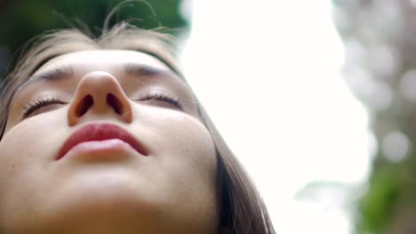 Low-angle-shot-woman-face-with-closed-eyes-meditates-feels-united-with-nature