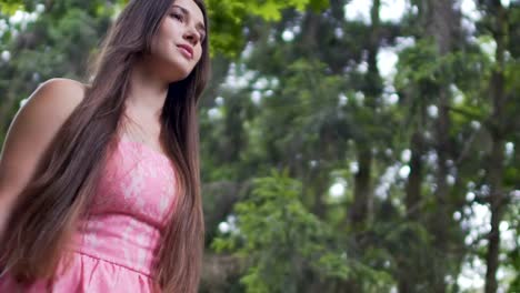 Beautiful-young-lady-in-red-dress-walks-outdoors,-brunette-female-in-forest