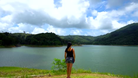 Una-chica-está-sola-en-el-borde-mirando-recto-en-el-lago-con-las-montañas