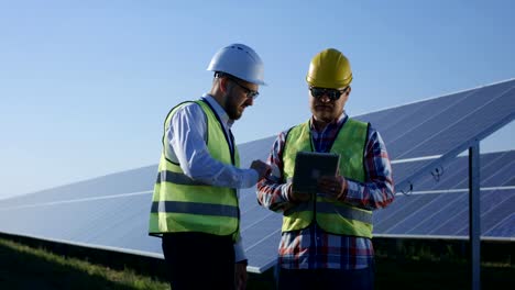 Zwei-elektrische-Arbeiter-überprüfen-von-Dokumenten-auf-einem-tablet