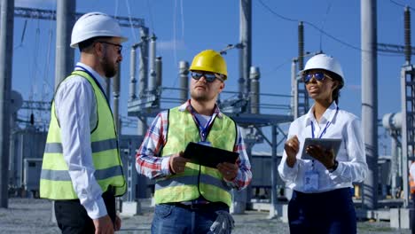 Tres-trabajadores-de-la-electricidad-revisar-documentos-en-forma-de-tabletas