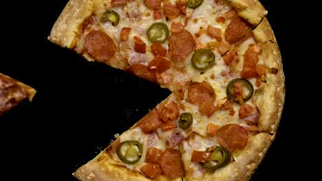 hand-takes-a-slice-of-pizza-on-a-black-background