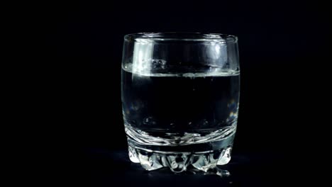 Wasser-in-einem-Glas-auf-einem-schwarzen-Hintergrund.-Slow-Motion.