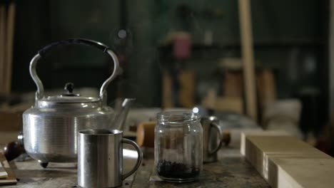 Steel-teapot,-stainless-mugs-and-a-can-of-tea-leaves