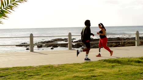 Seitenansicht-des-paar-Joggen-auf-der-Promenade-an-einem-sonnigen-Tag-4k