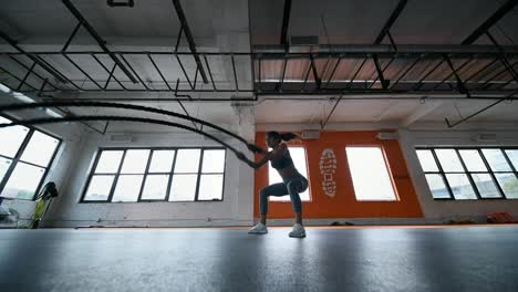 Mujer-atlética-en-un-gimnasio-de-ejercicios-con-cuerdas-de-batalla-durante-la-Cruz-entrenamiento-de-intervalo-de-alta-intensidad-de-entrenamiento.-Cámara-lenta.