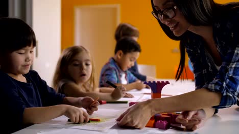 Maestro-de-jardín-de-niños-ayudando-a-niños-en-clase-de-arte