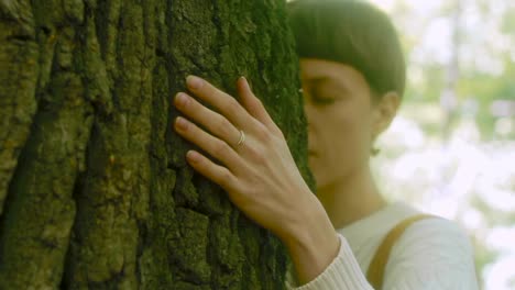 Niña-abraza-a-un-árbol-grande-en-el-bosque.