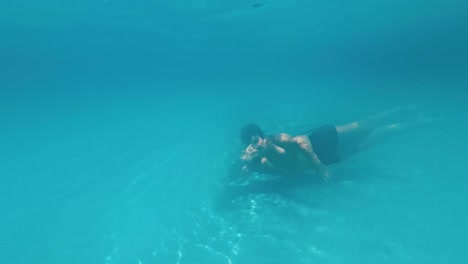 Young-guy-swims-underwater-in-a-swimming-pool