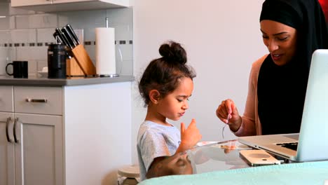 Joven-madre-dando-comida-a-su-hija-en-la-mesa-de-comedor-4k