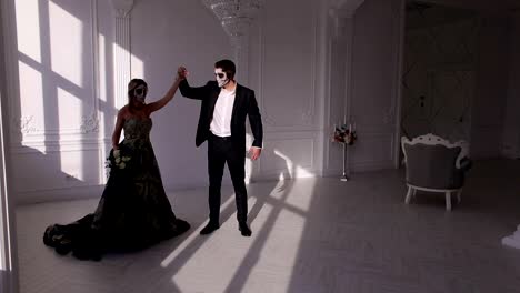 Pareja-en-trajes-y-maquillaje-para-Halloween,-bailan-en-una-habitación-blanca-brillante