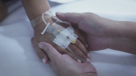 Mother-holding-hand-of-his-son-sick-bed-in-the-hospital.-Touch-the-hand-Slow-motion.-care-encouragement
