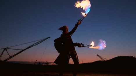 Ein-Mann-mit-einem-Flammenwerfer-bei-Sonnenuntergang-in-Zeitlupe.-Kostüm-für-Zombie-Apokalypse-und-Halloween.