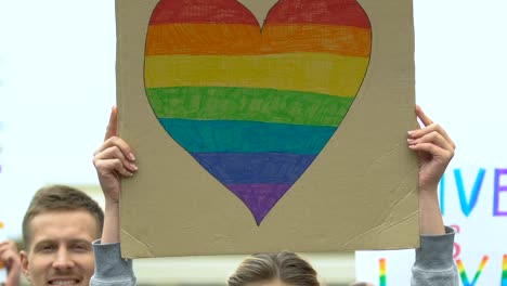 Junge-Leute,-die-Transparente-mit-LGBT-Regenbogenherz-und-Slogans-hissen,-Stolzmarsch