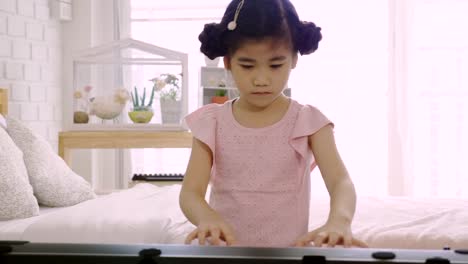 4K:-Asian-kid-girl-is-training-to-play-an-electric-piano.-Is-an-activity-that-trains-emotional-skills-And-the-body-well-Study-at-home-or-music-school-Music.-good-mental-health-and-good-mood.