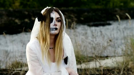 The-young-woman-with-spooky-make-up-for-Halloween-in-a-white-bride-dress.-4K