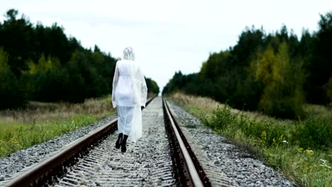 A-woman-dressed-in-wedding-gown-going-away-along-the-railway-among-the-forest.-4K