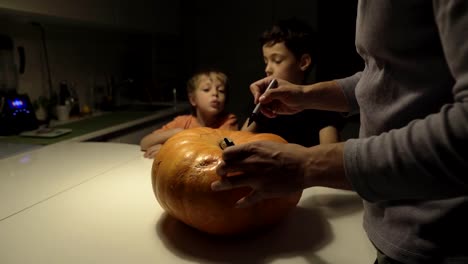 Fröhliches-Halloween.-Vater-und-Söhne-schnitzen-Kürbis-auf-dem-Tisch-im-Haus.-Familie-bereitet-sich-auf-den-Urlaub-vor.-Ansicht-von-oben.-Nahaufnahme