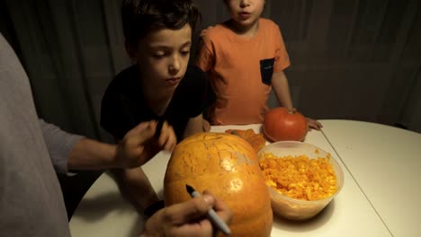 Feliz-Halloween.-Padre-e-hijos-tallando-calabaza-en-la-mesa-en-el-hogar.-Familia-preparándose-para-las-vacaciones.-Vista-superior.-De-cerca