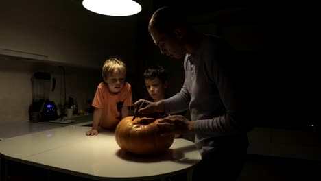 Fröhliches-Halloween.-Vater-und-Söhne-schnitzen-Kürbis-auf-dem-Tisch-im-Haus.-Familie-bereitet-sich-auf-den-Urlaub-vor.-Ansicht-von-oben.-Nahaufnahme