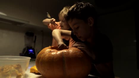 Feliz-Halloween.-Padre-e-hijos-tallando-calabaza-en-la-mesa-en-el-hogar.-Familia-preparándose-para-las-vacaciones.-Vista-superior.-De-cerca