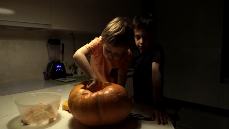 Feliz-Halloween.-Padre-e-hijos-tallando-calabaza-en-la-mesa-en-el-hogar.-Familia-preparándose-para-las-vacaciones.-Vista-superior.-De-cerca