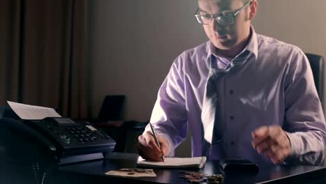 Sensación-de-cansancio.-Hombre-guapo-joven-frustrado-mirando-exhaustos-y-cubriendo-su-rostro-con-las-manos-mientras-está-sentado-en-su-lugar-de-trabajo-en-la-noche