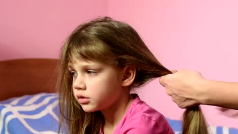 Mother-combing-her-long-hair-girls-and-braid-them-into-a-pigtail