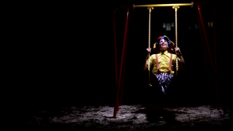 A-clown-rides-low-children-swings-in-the-dark.