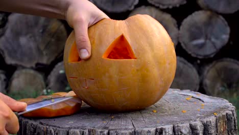 Man-carves-from-a-pumpkin-Jack-o'-lantern-in-the-backyard-on-a-tree-stump