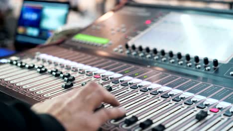 Audio-engineer-working-on-a-professional-console,-moving-faders,-mixing-music