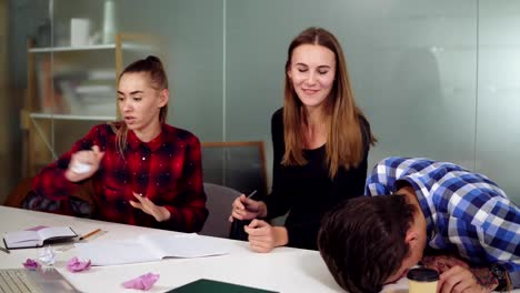 Group-of-tired-workers-in-a-creative-start-up-work-environment-holding-a-project-meeting-in-a-conference-room.-They-are-discussing-a-project-and-crumpling-papers,-working-hard-before-the-deadline