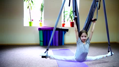 Schoolgirl-sits-on-twine-on-acrobatic-ropes