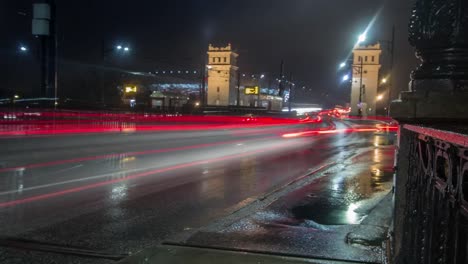 Lapso-de-tiempo-noche-de-ocupado,-mojada-la-calle-con-un-estadio-nacional-en-Varsovia-de-fondo