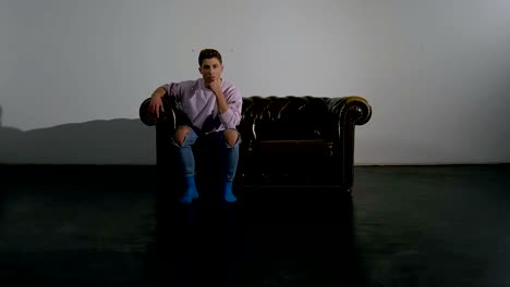 Young-Man-Sitting-Relaxed-on-Leather-Sofa-in-Studio